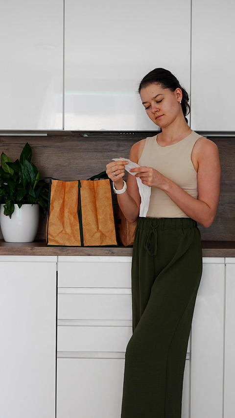 Woman checking grocery receipt and looking inside reusable shopping bags after