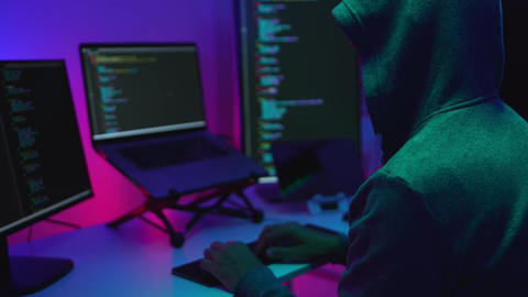 Hacker Programming on Dual Monitors Displaying Code in a Tech Workspace