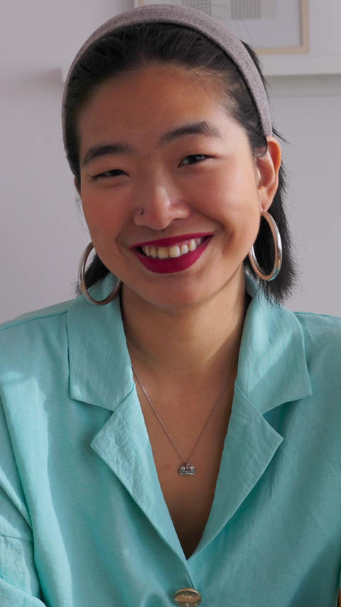Confident young asian woman smiling while sitting at her desk in a bright office