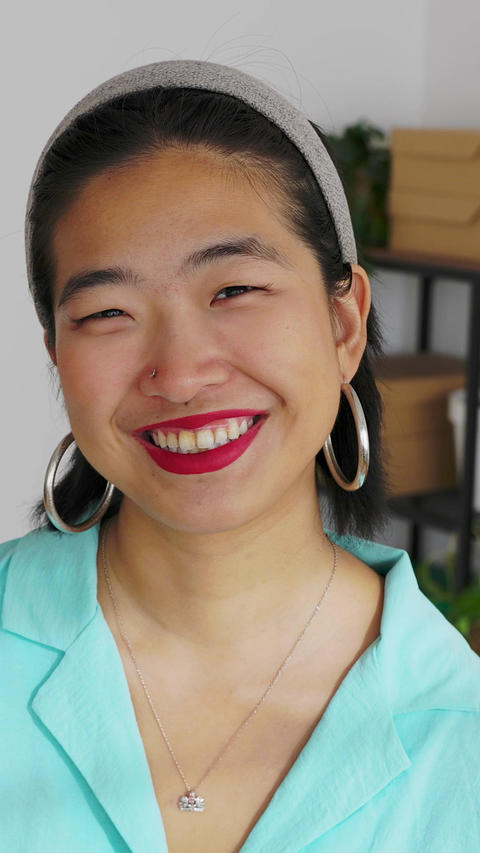 Confident asian woman smiling at camera in a minimalist bright home office