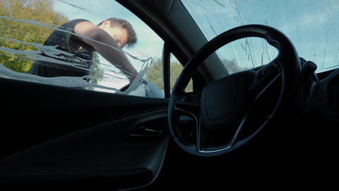 Interior view through wet windshield as attendant wipes exterior glass