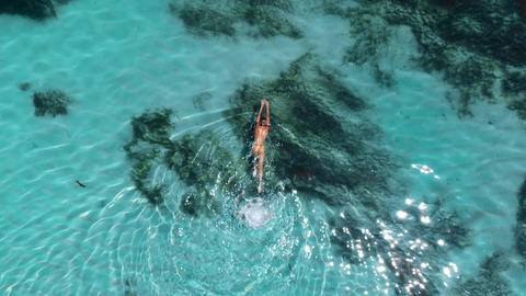 Young naked woman swims and floating in turquoise ocean. Aerial view, top view