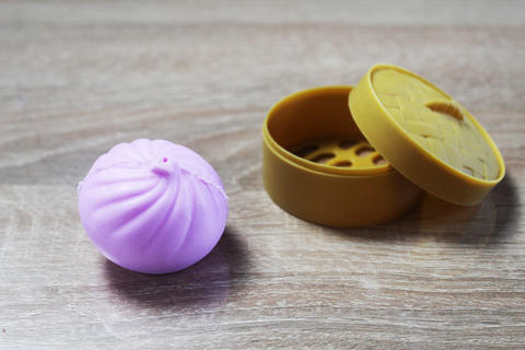 Anti-stress toy in the shape of a pink dumpling squishy lying near the box