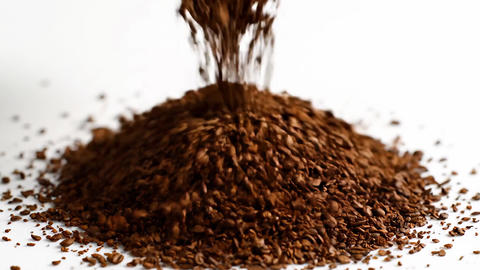 Granules of instant coffee falling to create a pile on a white surface. Process of pouring aromatic