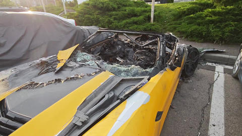 Burnt yellow sports car parked near other vehicles