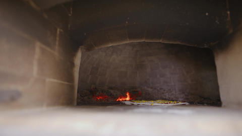 Small flame burning inside a dark brick hearth