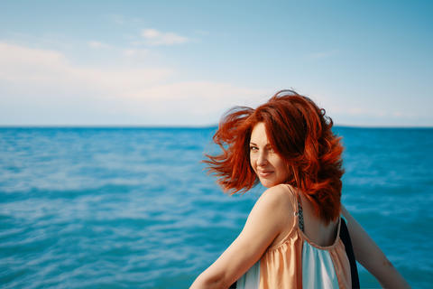 Redhead girl in a dress against the sea