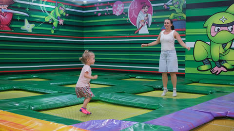 Mom and daughter jumping on trampolines together