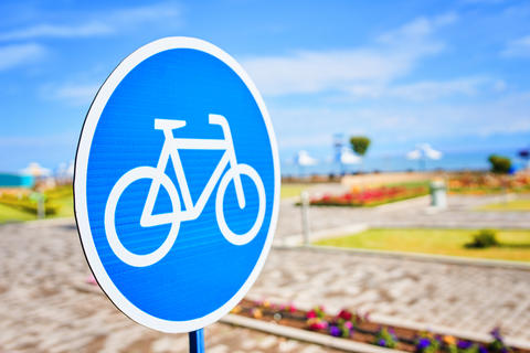 A blue and white sign with a bicycle image against a cloudy sky background