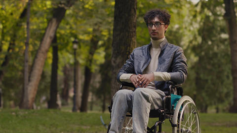 Young man standing up from wheelchair in park