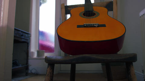 Acoustic guitar on wooden chair low shot
