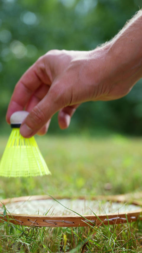 Badminton racket and shuttlecock lie on green grass. Outside recreation and