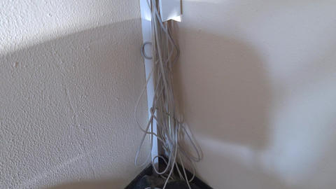 Open cable trunking with white cables, light and shadow on a textured wall