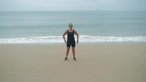 Woman exercising on beach near sea waves
