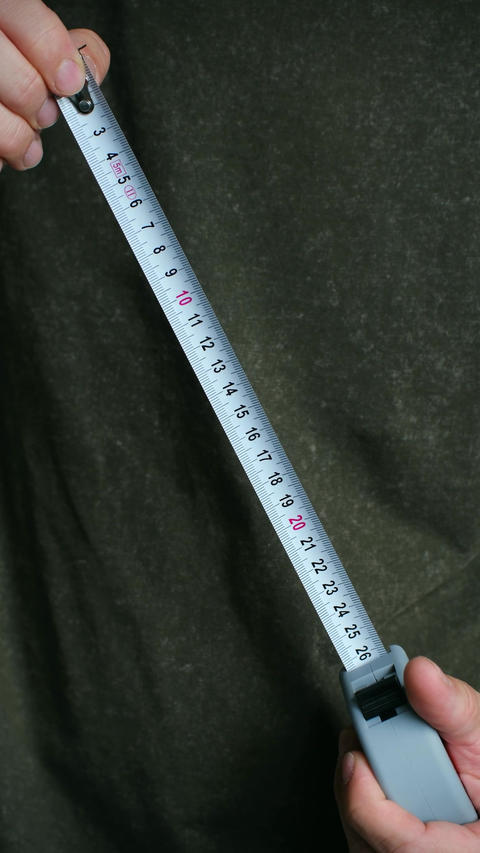 Person extending metal measuring tape for construction work