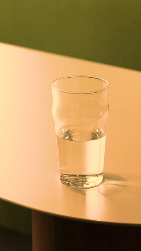 Half filled glass of water standing on table in minimal indoor composition