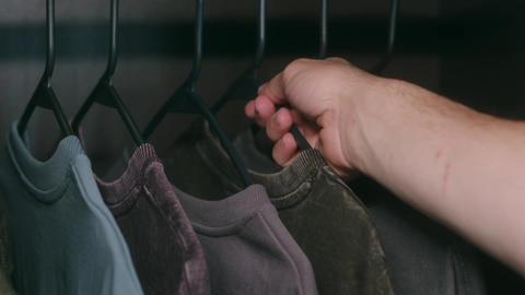 Person choosing a t shirt from a dark wardrobe