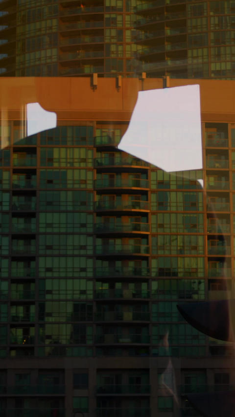 Tall apartment building reflected in glass window, orange structural frame and