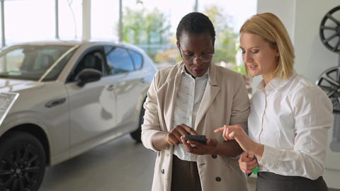 Car salesperson consulting a customer in a dealership showroom