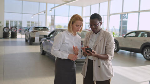 Two businesswomen discussing options in a car dealership