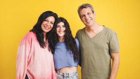 Happy family posing together on yellow background