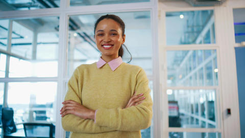 Smiling business woman standing with folded arms near glass wall. Looking at camera with confidence