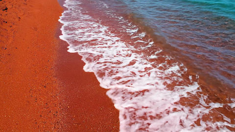 Turquoise Ocean Waves Washing Over A Bright Red Sand Beach