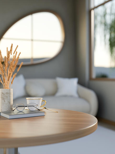 Glasses over book with coffee cup and dried rice spike vase on wooden table in living room or cafe