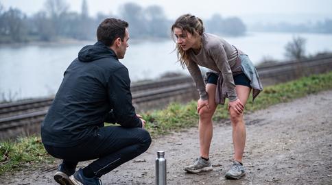 Coach Guiding Runner During Interval Recovery On Riverside Path