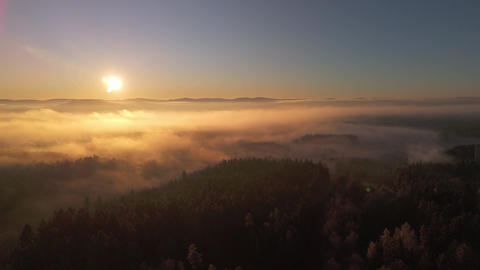 Aerial view of sea of fog over morning countryside under clear sky with sun
