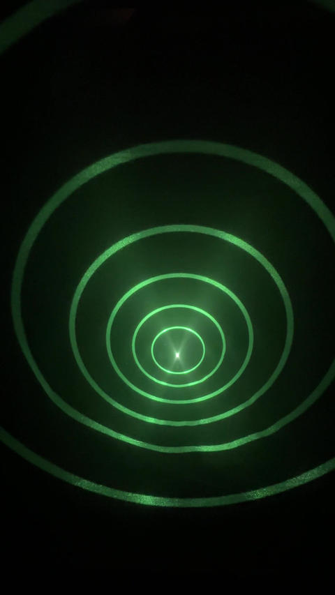 Green light beam creates concentric circles, transitioning to a bright white symbol
