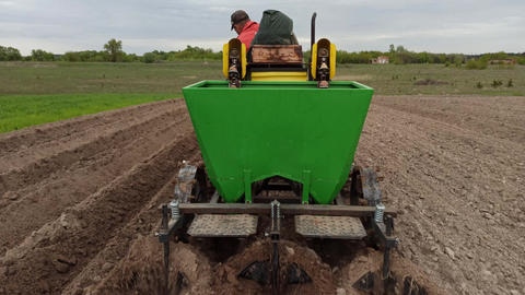 Tractor with potato planter machine working on agricultural field in September