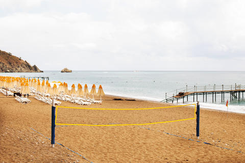 Beach volleyball net with sandy court by sea