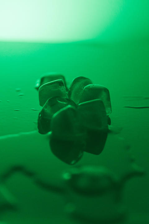 Pure clean Ice Cubes Melting On Mirror Surface In Neon Green Light Still Life