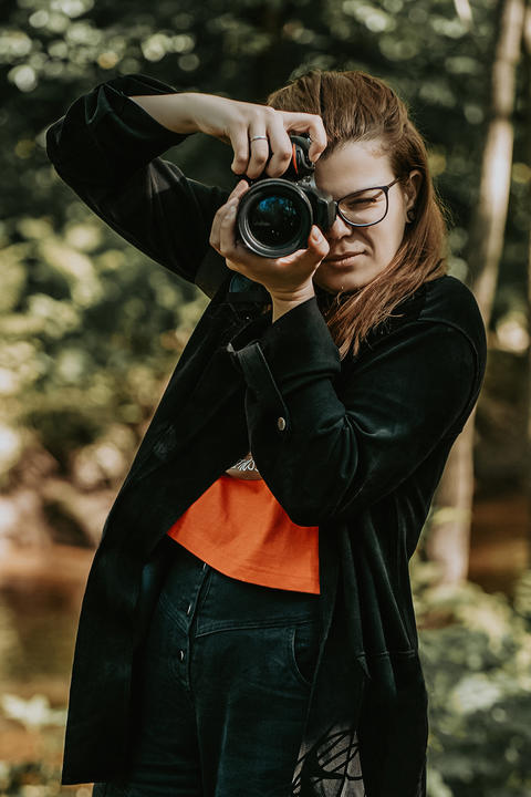 Portrait of woman photographer with camera at work photo session in park outside