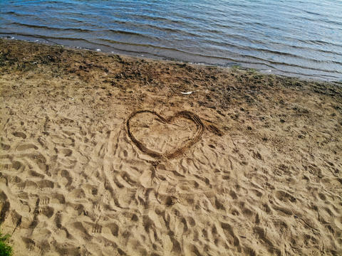 Love heart drawing in sand on lake side beach
