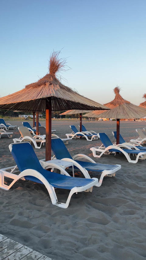 Sand beach Adriatic Sea with sunbeds and umbrellas at sunset, Ulcinj, Montenegro