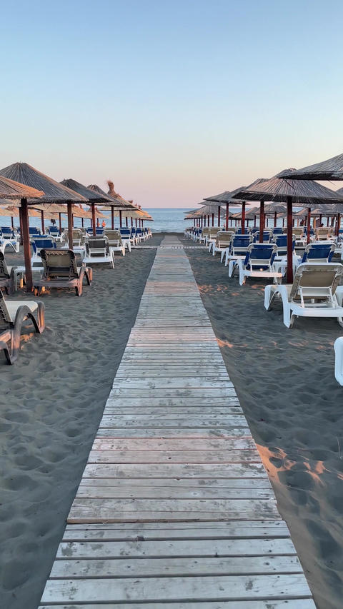 Sand beach Adriatic Sea with sunbeds and umbrellas at sunset, Ulcinj, Montenegro