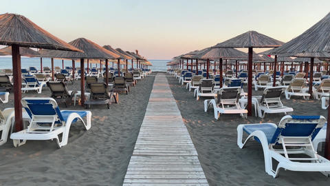 Sand beach Adriatic Sea with sunbeds and umbrellas at sunset, Ulcinj, Montenegro