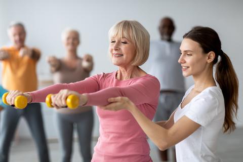 Senior Woman Exercising With Dumbbells In Gym Environment With Fitness