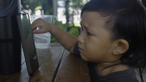 Toddler Is Sitting Watching Kids Songs On Mobile Phone 07