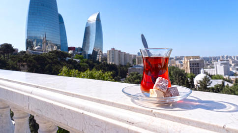 Traditional Azerbaijani black tea served in an elegant armudu glass with a scenic Baku cityscape