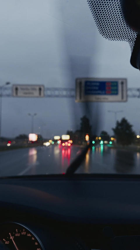 Blurry rainy roadway view from inside car with wet reflections, traffic lights