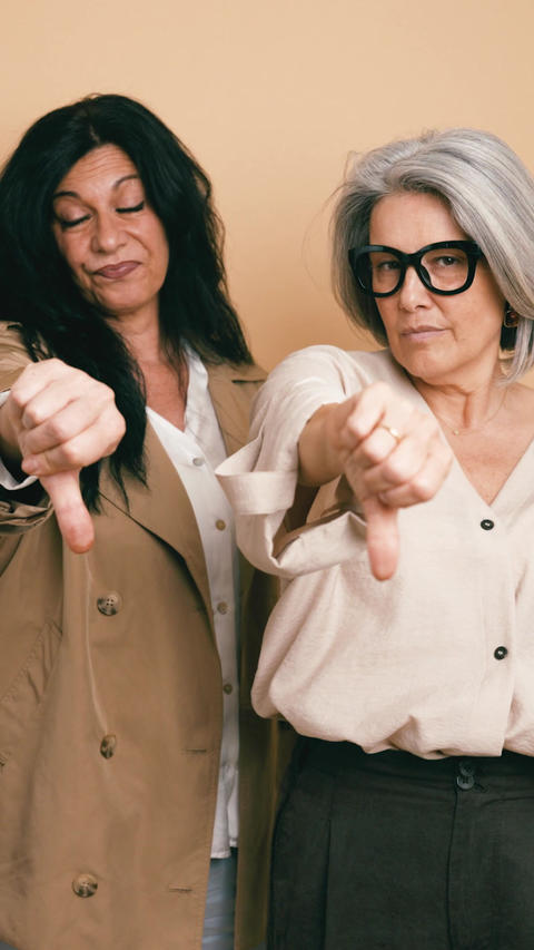 Disappointed mature women showing thumbs down gesture. Vertical