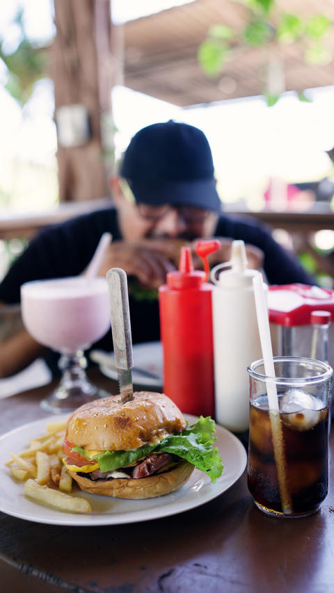 Man enjoying burger, fries, and milkshake at local grill