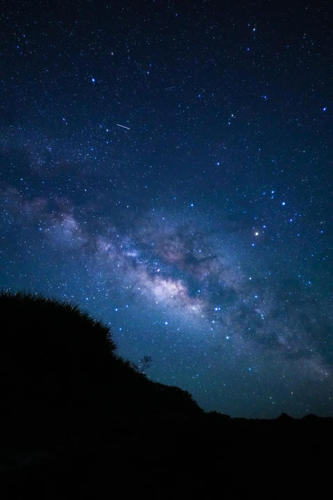 Person silhouette looking up at the Milky Way in Miyakojima, vertical photo