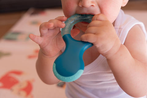 Baby teething on colorful teether for gum relief