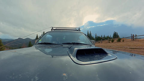 Front view of a rugged off road vehicle beneath dramatic clouds, Hood mounted travel footage with