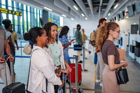 Diverse travelers waiting in line at airport check-in