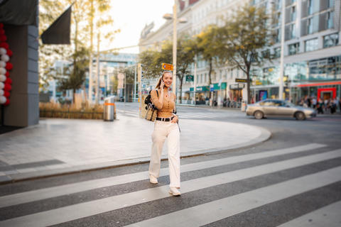 Young adult woman talking on phone crossing street in Vienna